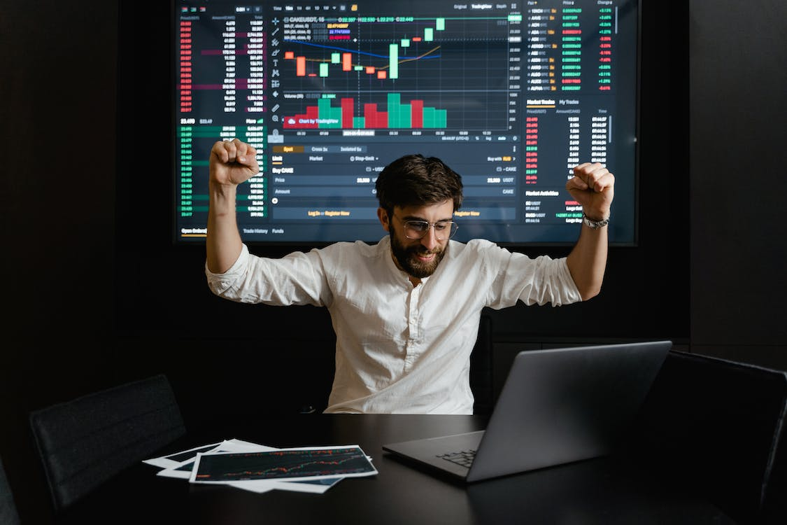 A businessman raising his hands in celebration, symbolizing success achieved through effective cash flow management.