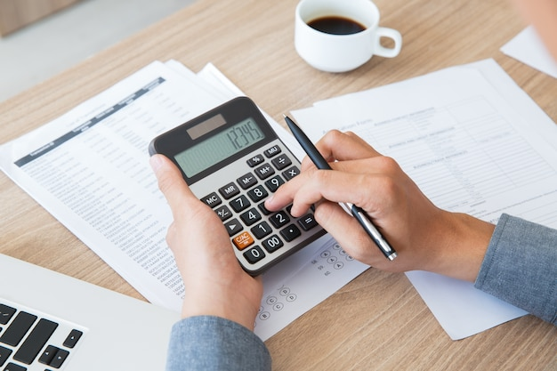 Person using a calculator, representing financial transactions in a corporate setup.