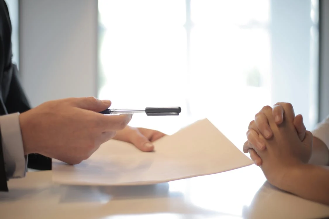 a person giving a pen to another person for signing forms