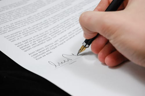 Person signing a business document to formalize a corporate partnership agreement.