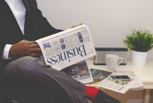 Person reading a business magazine for insights on financial and tax planning strategies.