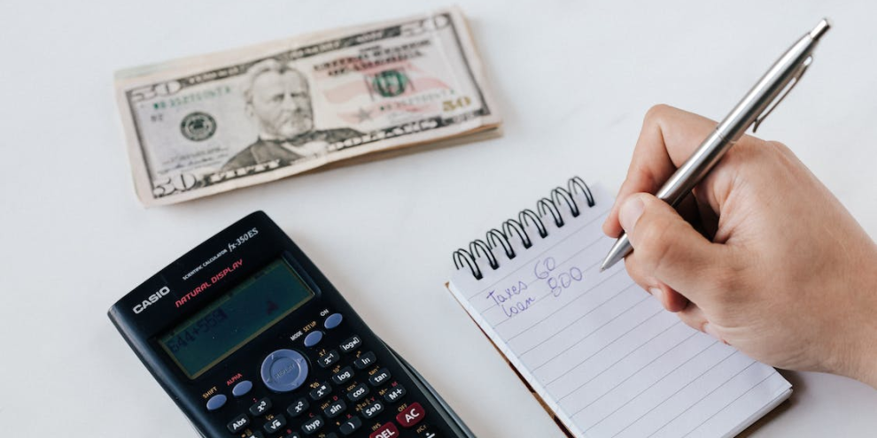 A close-up of a person writing numbers in a notebook, representing financial planning and budgeting.